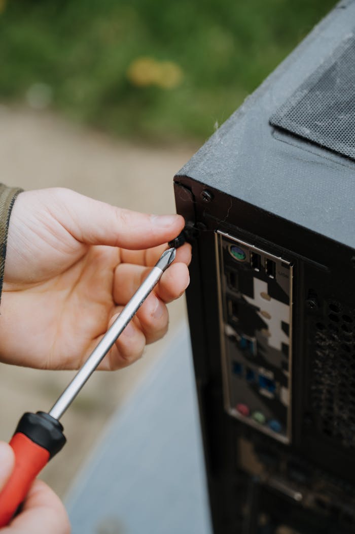 Close-up of a person tightening screws on a PC case for maintenance.